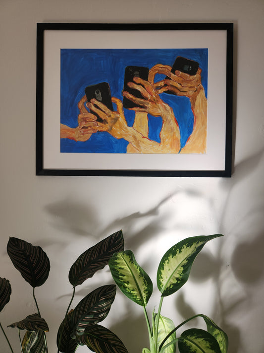 An original gouache and oil pastel painting titled 'At a Party' by Neta Singer. The artwork features images of hands holding phones in various positions against a blue background, with a setting of plants hanging on a wall. The painting has white borders and is framed with a wooden frame and matte glass. The size including the frame is 49x63 cm.